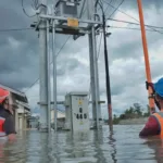 Petugas PLN bertugas di tengah banjir.