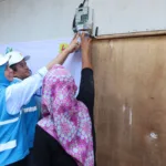 Simbolis penyalaan sambungan listrik gratis program "Berbagi Cahaya, Menumbuhkan Harapan" oleh Direktur Keuangan PLN, Sinthya Roesly (kiri), bersama General Manager PLN Unit Induk Distribusi Banten, Mohammad Joharifin (tengah) di rumah Juniah (kanan), salah satu penerima manfaat di Desa Pejamben, Kecamatan Carita, Kabupaten Pandeglang, Banten, pada Jumat (17/10).