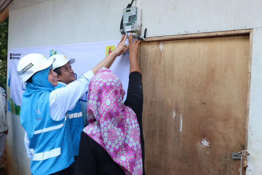 Simbolis penyalaan sambungan listrik gratis program "Berbagi Cahaya, Menumbuhkan Harapan" oleh Direktur Keuangan PLN, Sinthya Roesly (kiri), bersama General Manager PLN Unit Induk Distribusi Banten, Mohammad Joharifin (tengah) di rumah Juniah (kanan), salah satu penerima manfaat di Desa Pejamben, Kecamatan Carita, Kabupaten Pandeglang, Banten, pada Jumat (17/10).