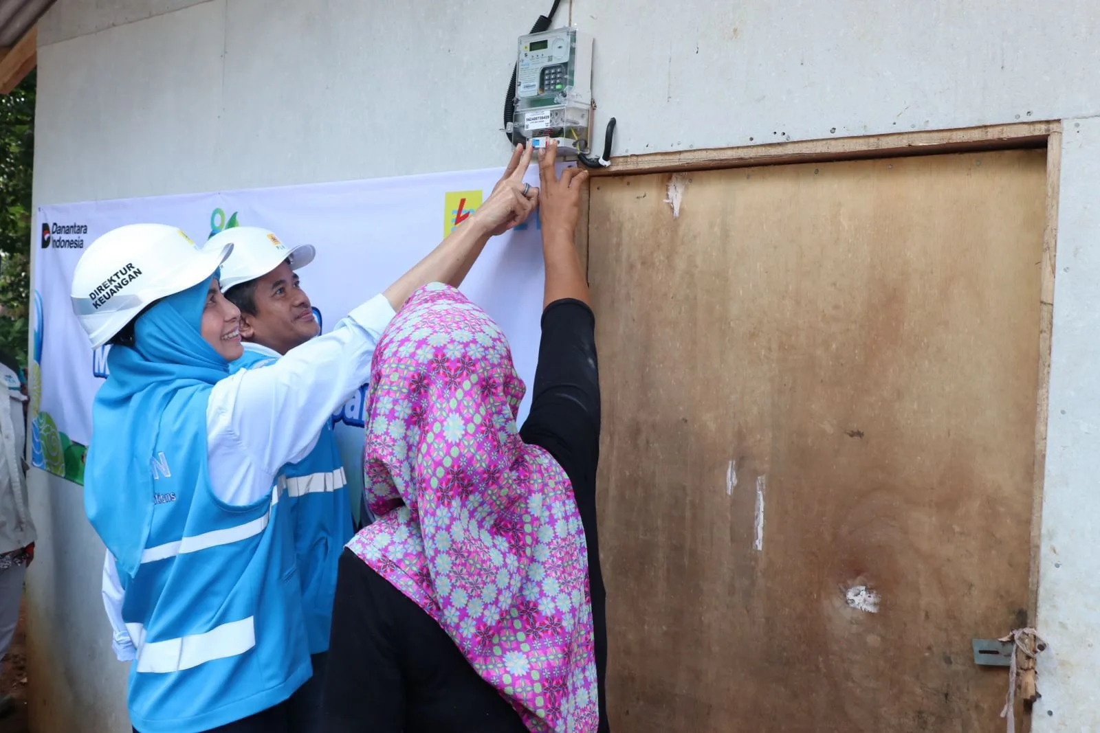 Simbolis penyalaan sambungan listrik gratis program "Berbagi Cahaya, Menumbuhkan Harapan" oleh Direktur Keuangan PLN, Sinthya Roesly (kiri), bersama General Manager PLN Unit Induk Distribusi Banten, Mohammad Joharifin (tengah) di rumah Juniah (kanan), salah satu penerima manfaat di Desa Pejamben, Kecamatan Carita, Kabupaten Pandeglang, Banten, pada Jumat (17/10).